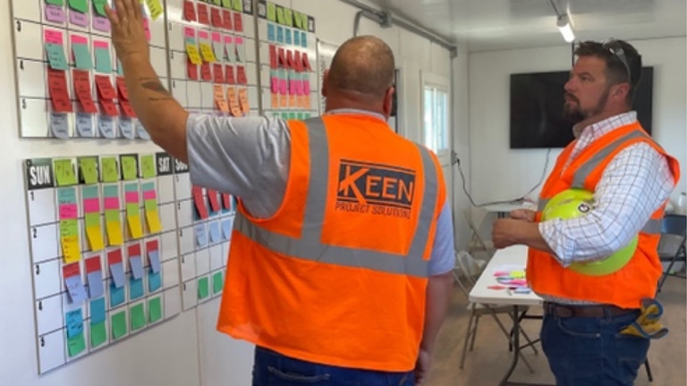 Keen contractors adding post its to a wall